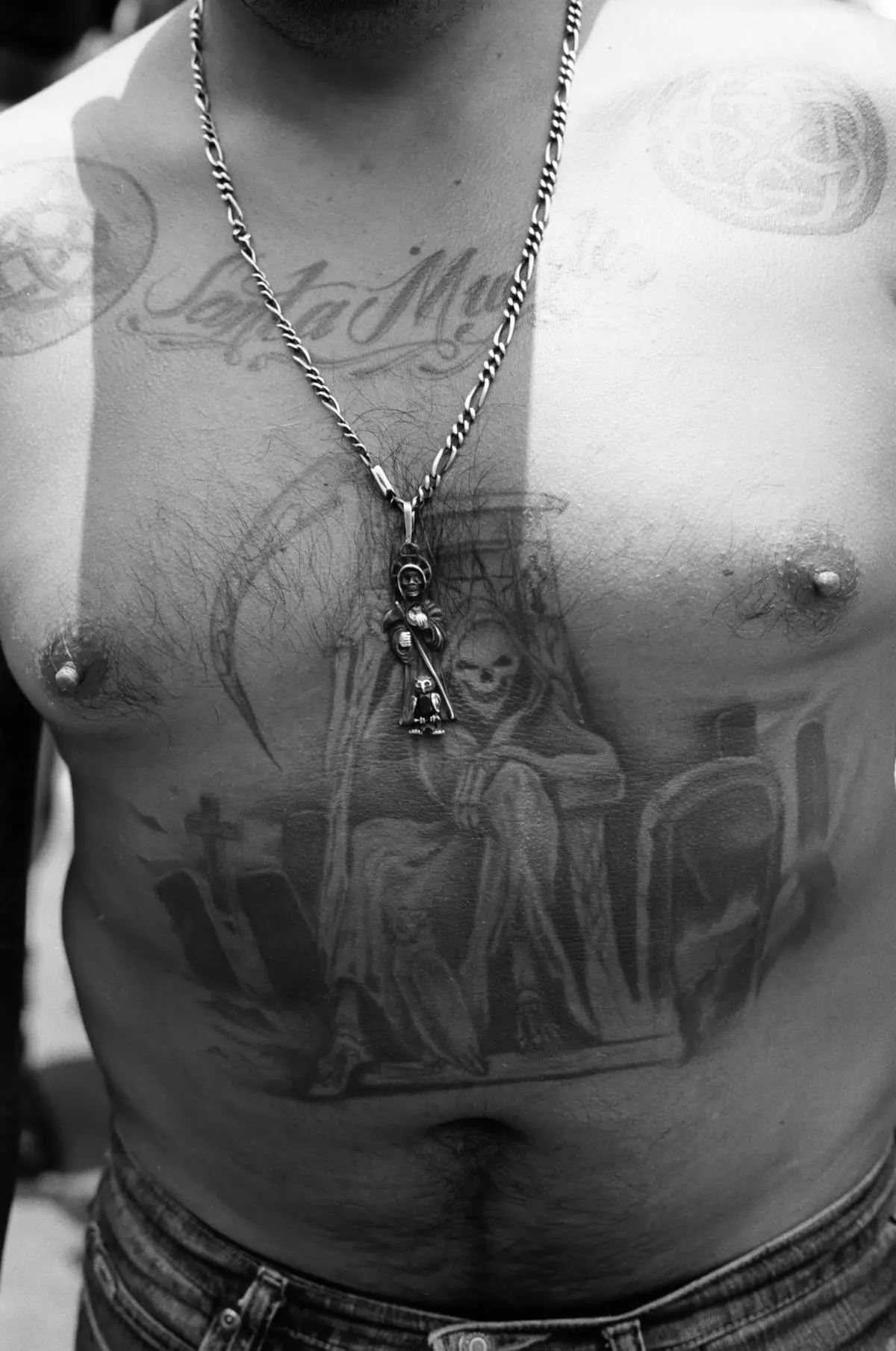 Black-and-grey Santa Muerte chest piece with fine cursive script lettering