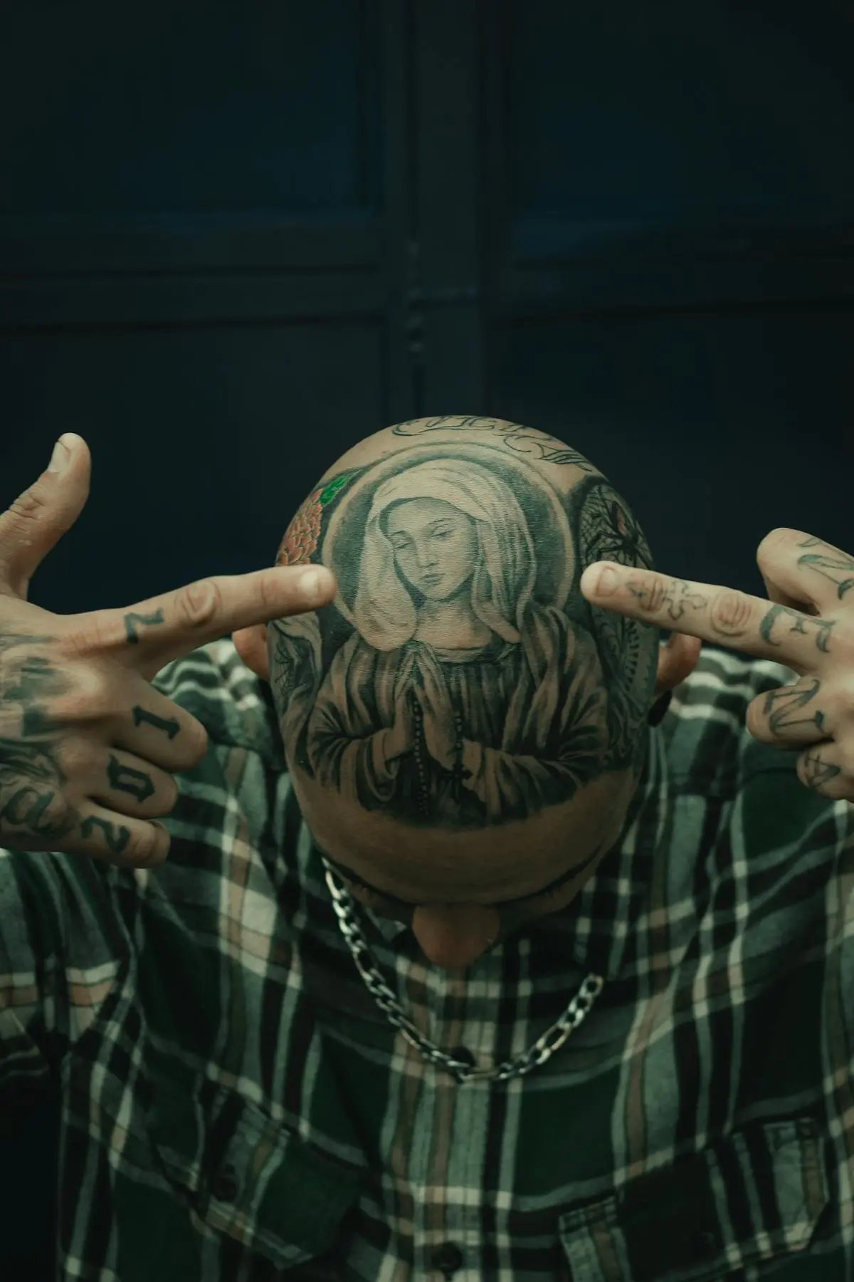 Black-and-grey Virgin Mary praying with a rosary tattooed on the scalp