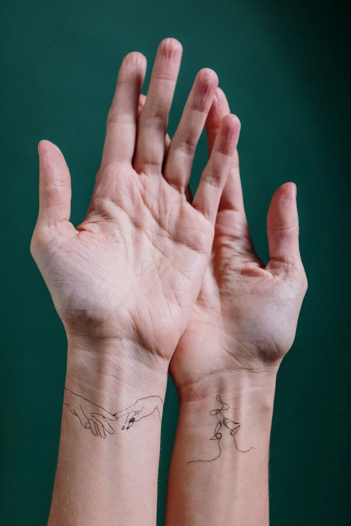 Delicate single-line figure tattoos on both inner wrists
