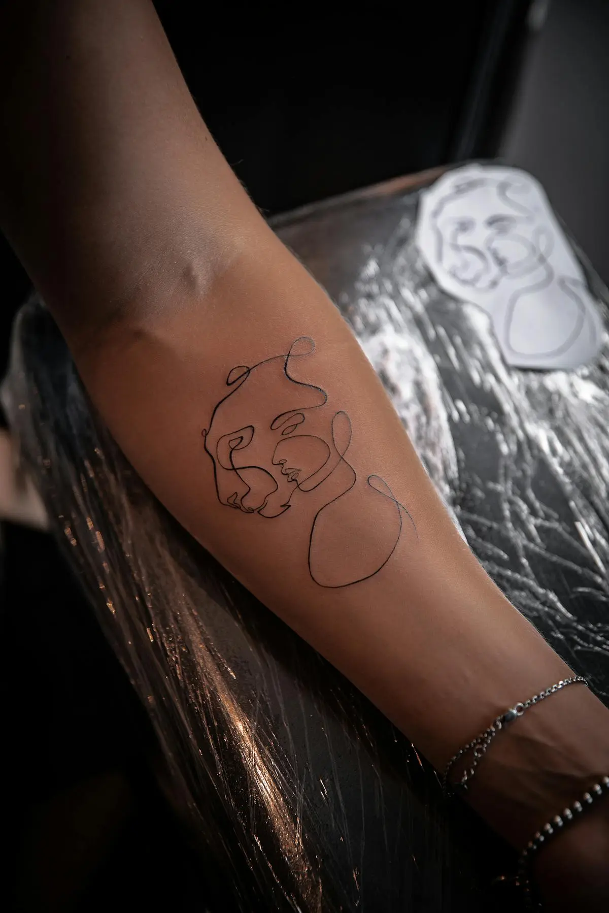 Continuous single-line abstract faces on the forearm