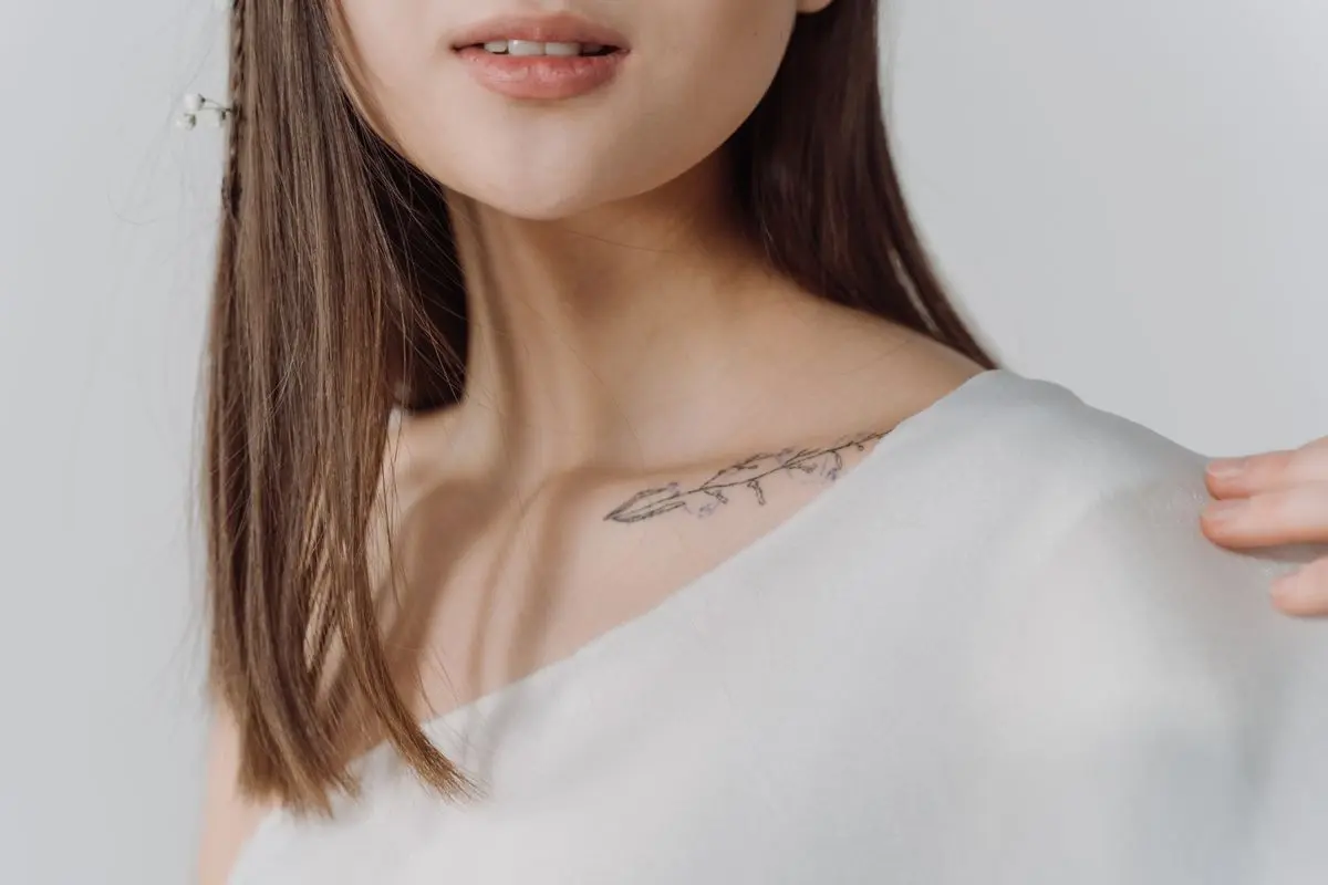 Fine-line floral branch along the collarbone