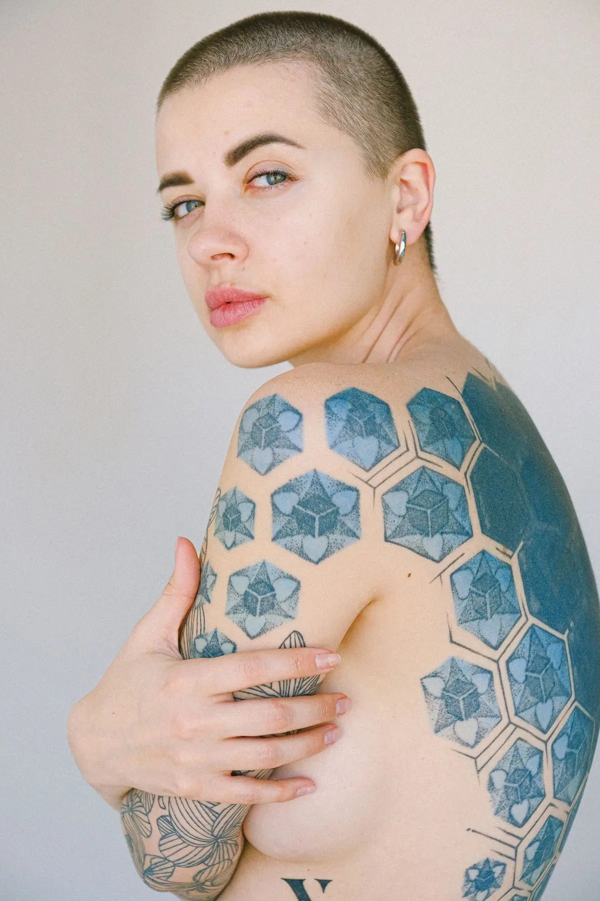 Blue dotwork hexagonal honeycomb pattern with cube facets across the shoulder