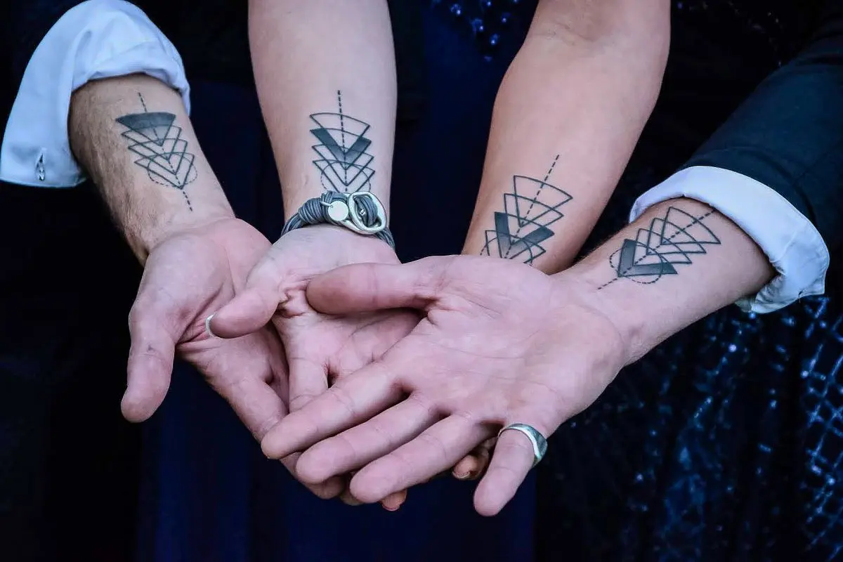 Matching stacked-triangle linework tattoos on four forearms