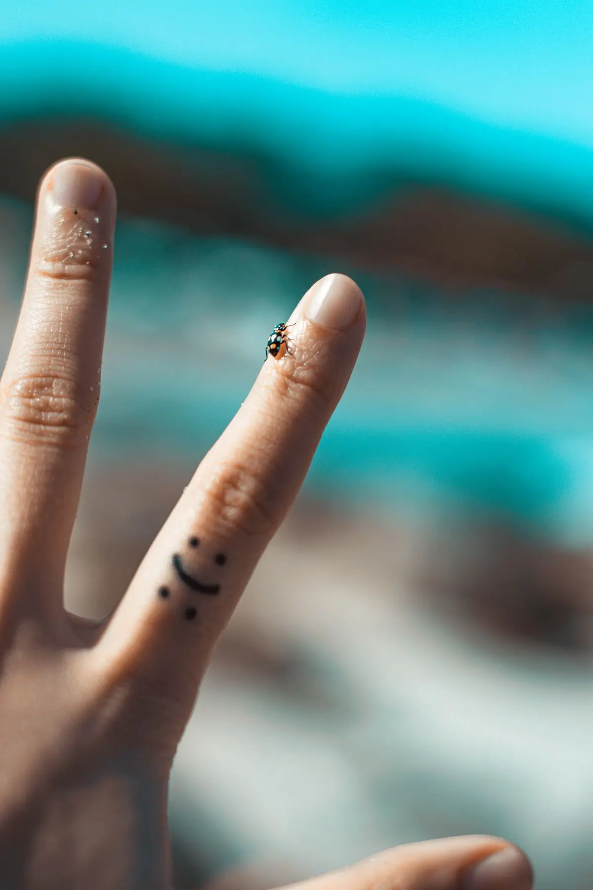 Tiny smiley-face tattoo on the side of a finger