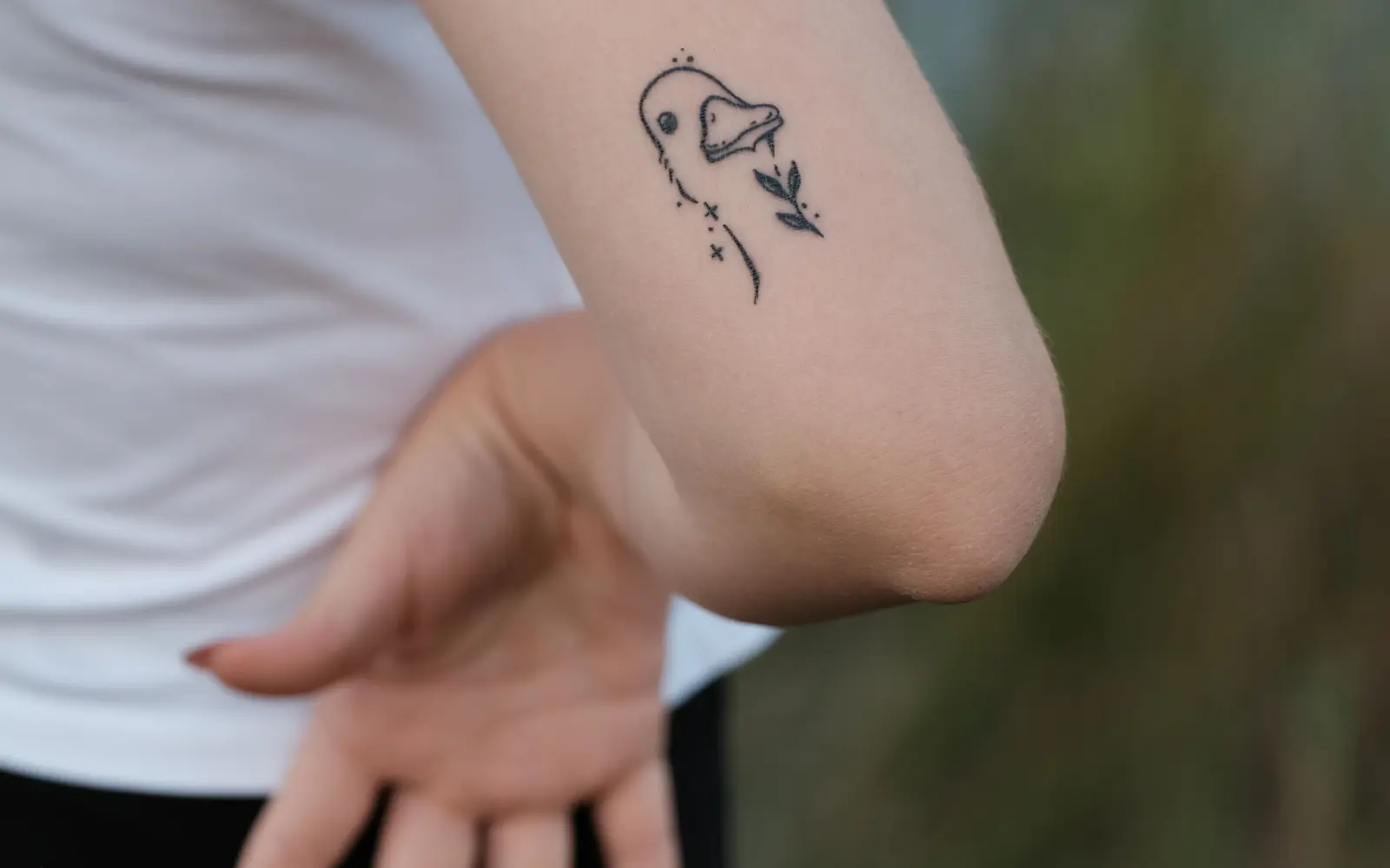 Close-up minimalist tattoo on the back of a woman's arm