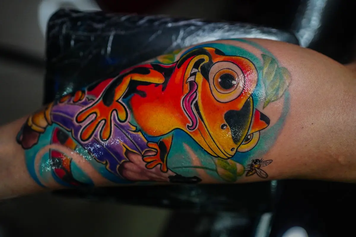 Neo-traditional tree frog in vibrant orange, purple, and teal with bold varied outlines on the forearm