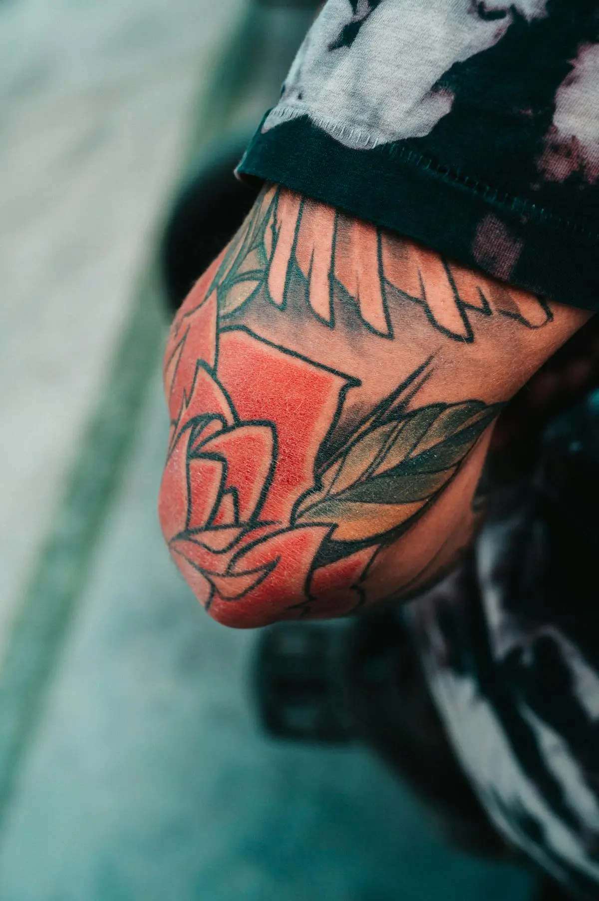 Bold-outline traditional rose in flat red and green on the hand