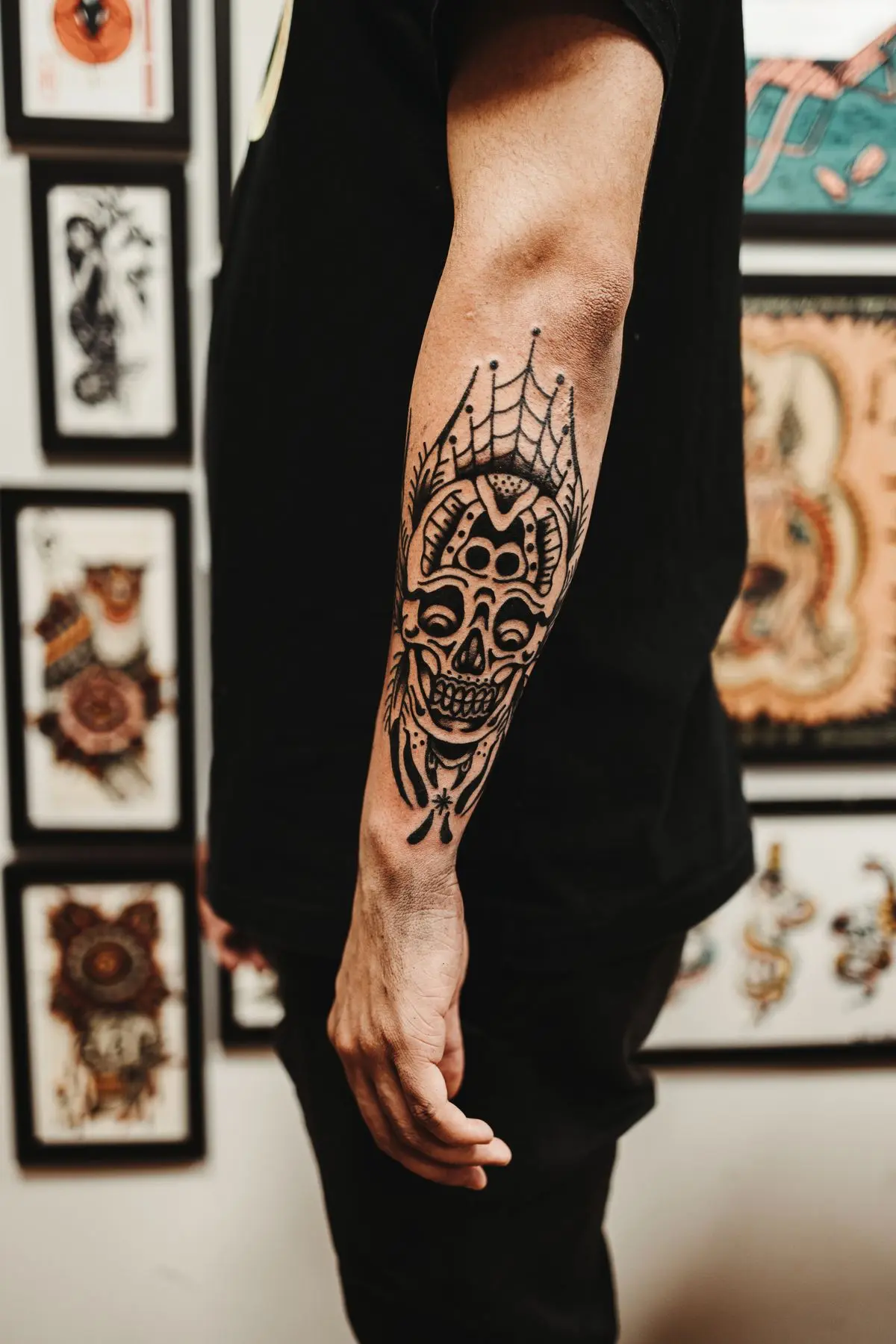 Black-outline old-school skull with a spiderweb crown on the forearm
