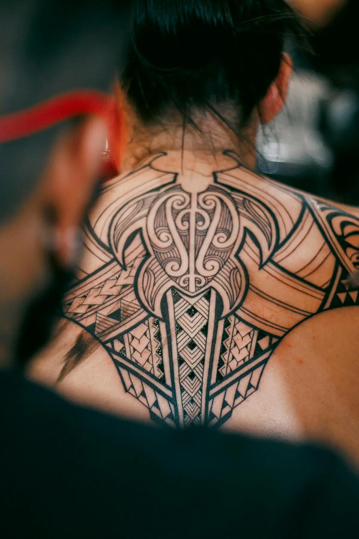 Bold black Polynesian and Maori tribal piece across the back of the neck and shoulders
